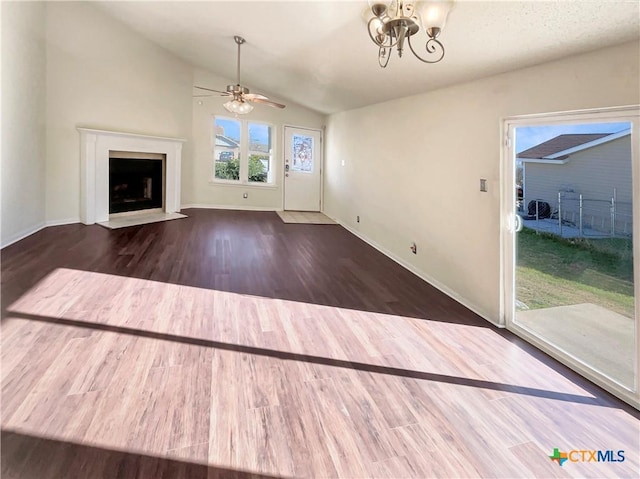 unfurnished living room featuring ceiling fan with notable chandelier, lofted ceiling, and dark wood-type flooring