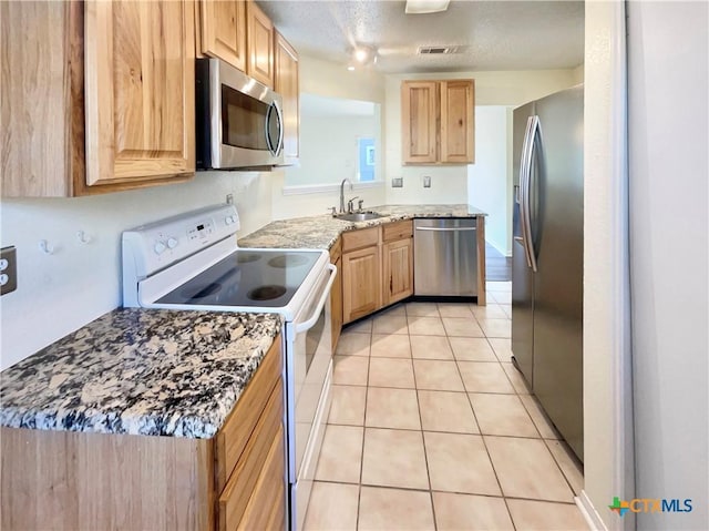 kitchen featuring sink, stainless steel appliances, a textured ceiling, light brown cabinetry, and light tile patterned flooring