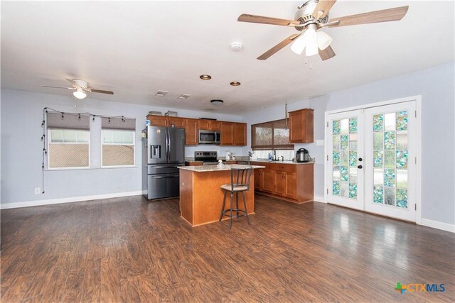2206 Grandon Cir, Killeen, TX 76541 - kitchen with a ceiling fan, appliances with stainless steel finishes, a center island, brown cabinets, and dark wood-style flooring