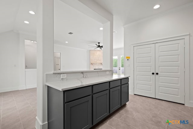 kitchen with kitchen peninsula, ornamental molding, gray cabinets, ceiling fan, and light stone countertops