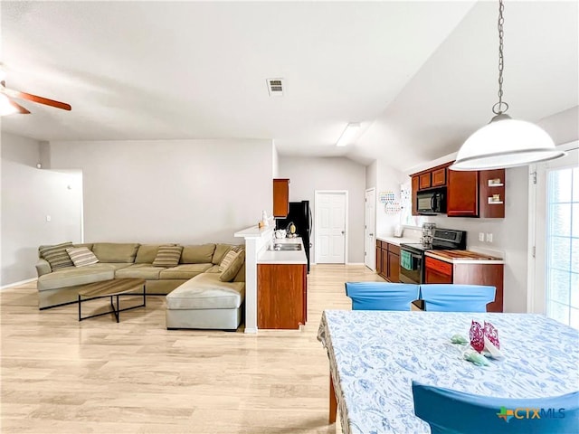 144 Calcite Ln, Jarrell, TX 76537 - kitchen with stainless steel electric range, black microwave, open floor plan, ceiling fan, and light wood-style floors