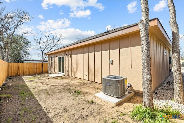 view of property exterior featuring central AC, board and batten siding, and fence