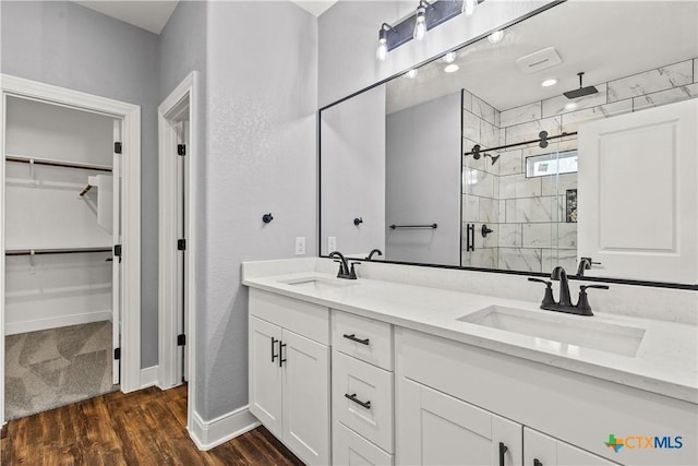 full bath featuring wood finished floors, a sink, a walk in closet, and a shower stall