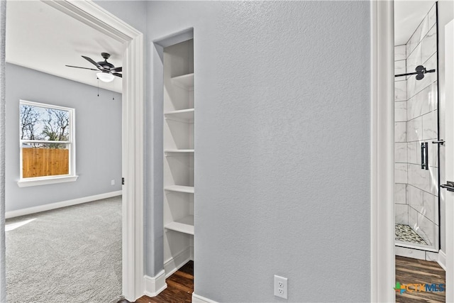 interior space featuring baseboards, dark colored carpet, and a textured wall