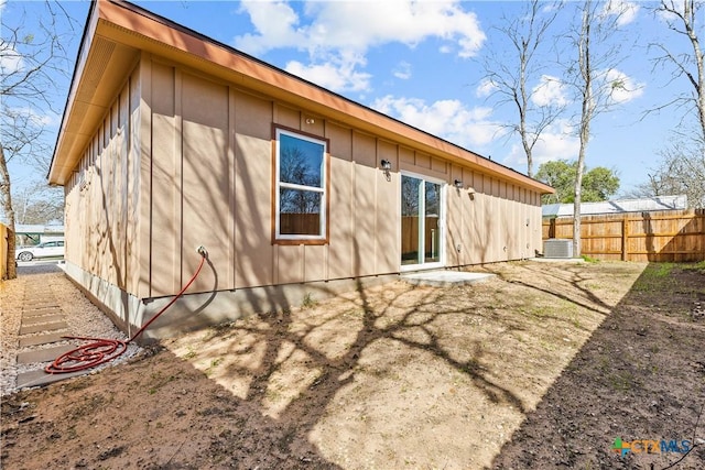 back of property with board and batten siding, fence, and central air condition unit