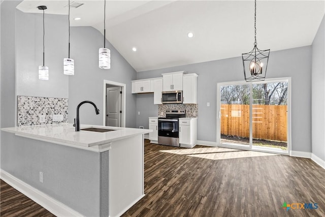 kitchen with dark wood-style flooring, stainless steel appliances, tasteful backsplash, white cabinetry, and a sink