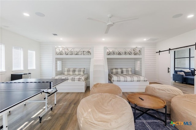 bedroom featuring a barn door, hardwood / wood-style flooring, and ceiling fan