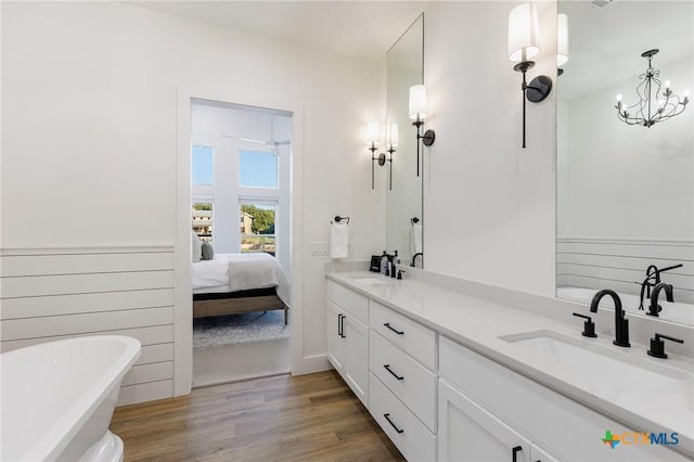 bathroom featuring hardwood / wood-style flooring, vanity, a washtub, and an inviting chandelier