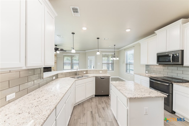 kitchen with stainless steel appliances, white cabinetry, ornamental molding, backsplash, and a kitchen island