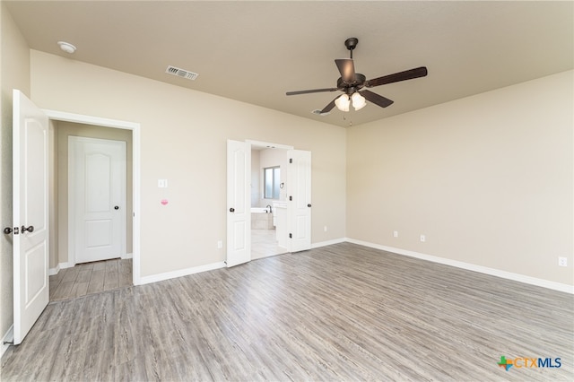 unfurnished bedroom with hardwood / wood-style floors, ceiling fan, and connected bathroom