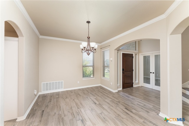 unfurnished dining area with french doors, light hardwood / wood-style flooring, crown molding, and an inviting chandelier