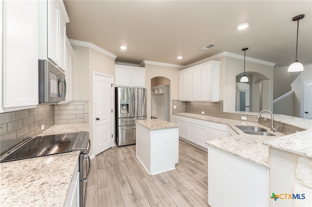 kitchen with stainless steel appliances, decorative light fixtures, light stone countertops, sink, and a center island