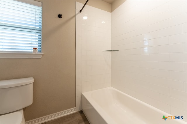 bathroom with toilet, tiled shower / bath, hardwood / wood-style flooring, and a healthy amount of sunlight