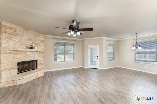 unfurnished living room with hardwood / wood-style floors, a fireplace, crown molding, and ceiling fan with notable chandelier