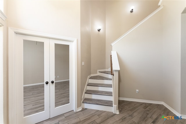 stairs with french doors and wood-type flooring