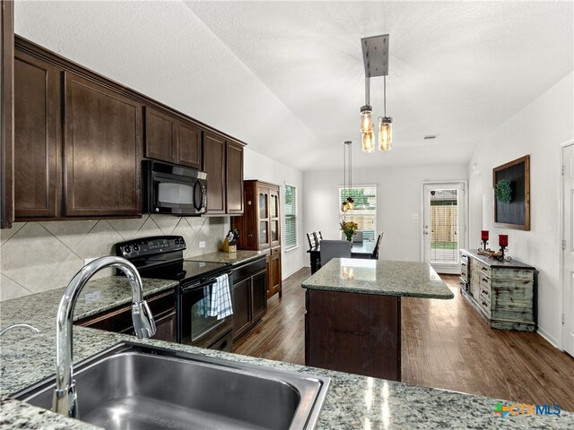 2416 Kolton St, New Braunfels, TX 78130 - kitchen featuring black appliances, a center island, dark brown cabinetry, decorative backsplash, and pendant lighting