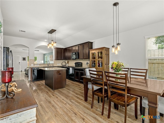 2416 Kolton St, New Braunfels, TX 78130 - kitchen featuring black appliances, arched walkways, a kitchen island, dark brown cabinetry, and tasteful backsplash