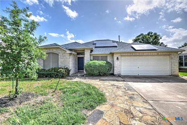 1900 Rutherford Dr, Leander, TX 78641 - view of front facade featuring stone siding, concrete driveway, a garage, roof mounted solar panels, and a shingled roof