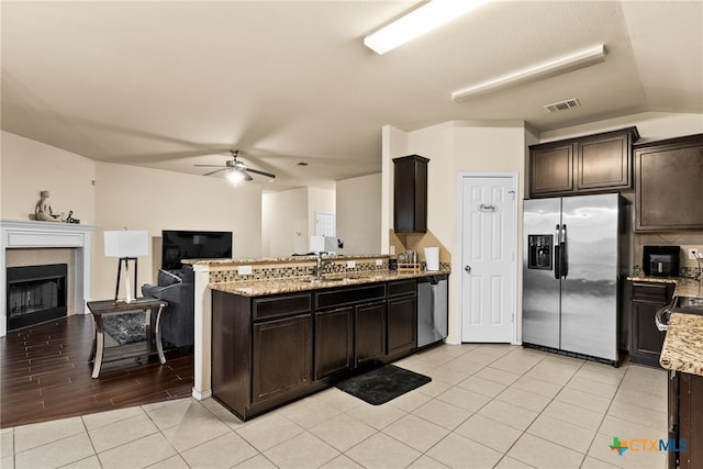 kitchen with dark brown cabinets, light stone countertops, and appliances with stainless steel finishes