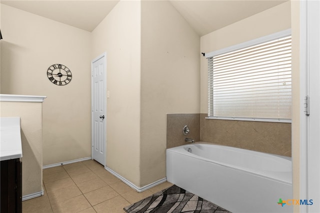 bathroom with tile patterned flooring, vanity, a tub to relax in, and vaulted ceiling