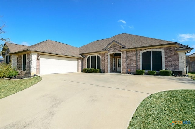 french country style house with a garage, driveway, brick siding, and roof with shingles