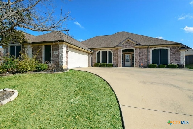 french provincial home featuring brick siding, a shingled roof, concrete driveway, an attached garage, and a front yard