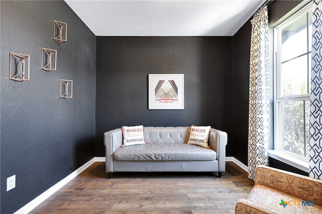 living area with a wealth of natural light and hardwood / wood-style flooring