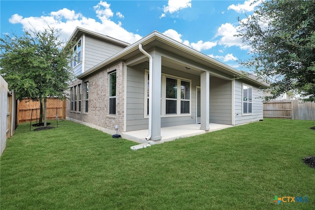 rear view of house featuring a patio area and a lawn