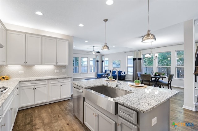 kitchen with dishwasher, decorative light fixtures, ceiling fan with notable chandelier, and a center island with sink