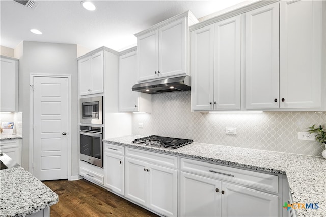 kitchen with appliances with stainless steel finishes, tasteful backsplash, light stone counters, dark wood-type flooring, and white cabinetry