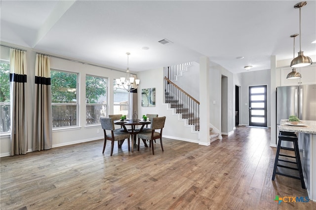 dining space featuring wood-type flooring and an inviting chandelier