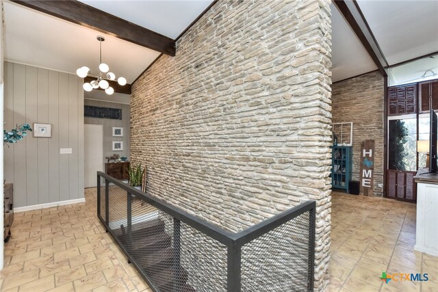 corridor with lofted ceiling with beams, wood walls, and an inviting chandelier