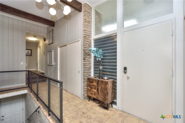 foyer entrance with beam ceiling and wooden walls