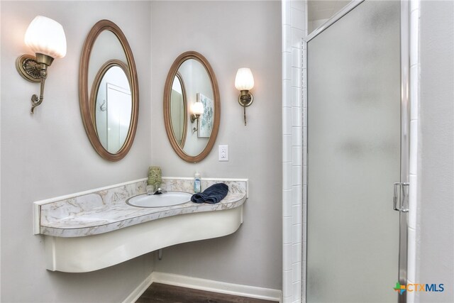 bathroom with wood-type flooring, an enclosed shower, and sink