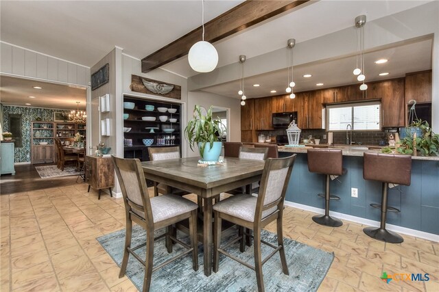 dining space with beam ceiling, built in features, sink, and a chandelier