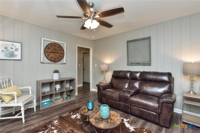 living room with ceiling fan, wooden walls, and dark hardwood / wood-style floors