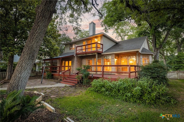 back house at dusk featuring a deck