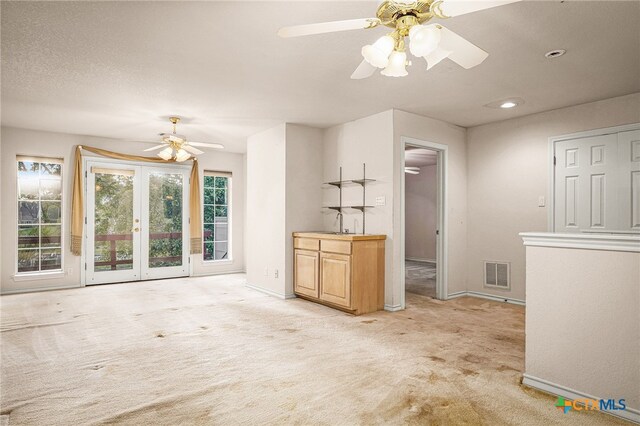 unfurnished living room featuring light carpet and ceiling fan