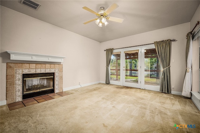 unfurnished living room featuring carpet floors, ceiling fan, and a tile fireplace