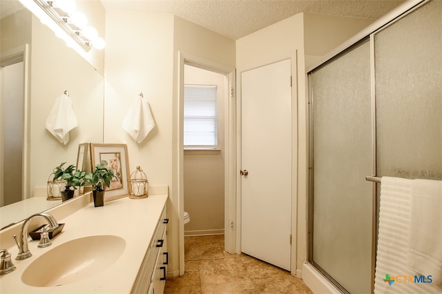 bathroom featuring vanity, a textured ceiling, and a shower with door