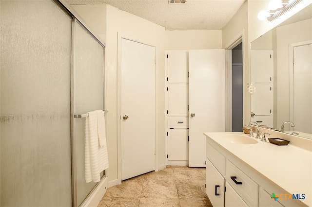 bathroom with vanity, a textured ceiling, and a shower with shower door