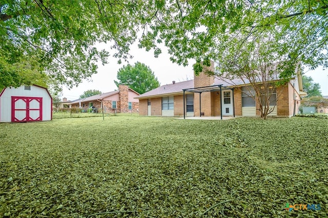 rear view of property featuring a storage unit and a lawn