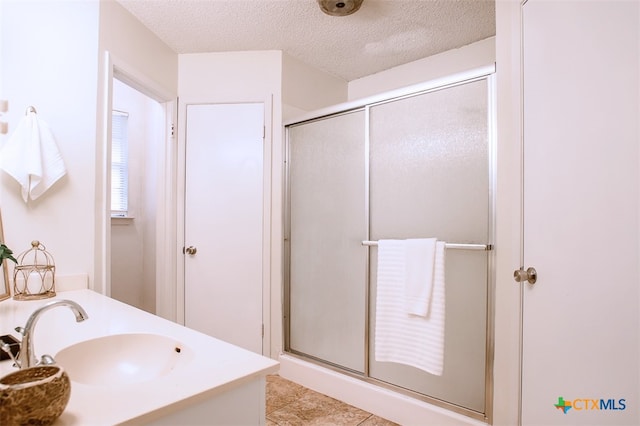 bathroom featuring vanity, an enclosed shower, a textured ceiling, and tile patterned floors