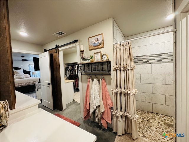 ensuite bathroom with walk in shower, connected bathroom, visible vents, ceiling fan, and concrete flooring