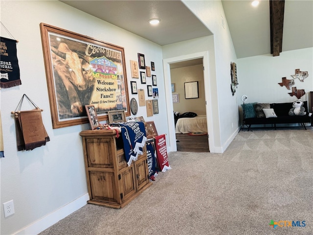 hallway featuring carpet flooring, baseboards, and beam ceiling