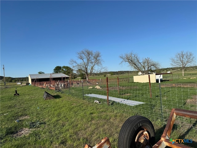 view of yard featuring a rural view, an outbuilding, and fence