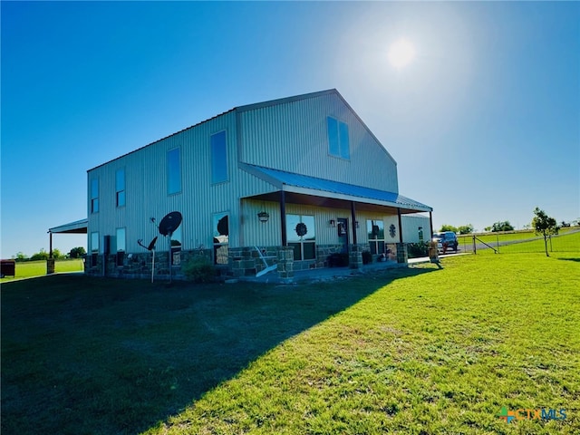 back of house with metal roof and a lawn