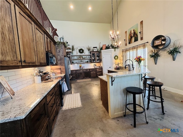 kitchen featuring tasteful backsplash, concrete floors, open shelves, a kitchen bar, and appliances with stainless steel finishes