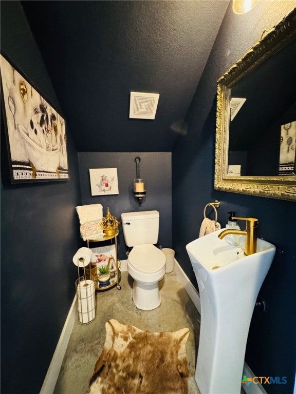 bathroom with toilet, baseboards, lofted ceiling, and visible vents