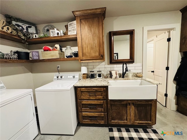 washroom featuring washing machine and dryer, a sink, and cabinet space